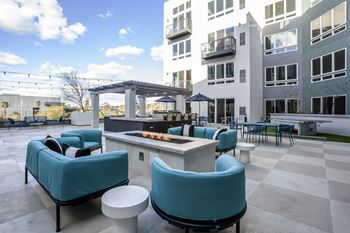 an outdoor lounge area with a fire pit and chairs
